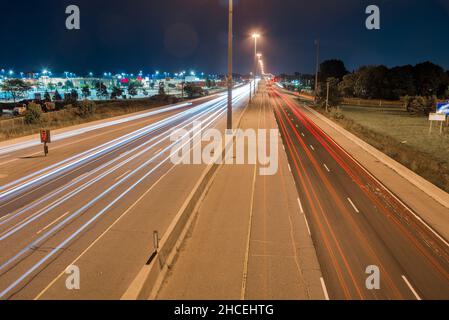 Nachtsicht von einer Autobahn mit leichten Wegen, die von vorbeifahrenden Fahrzeugen verlassen werden Stockfoto