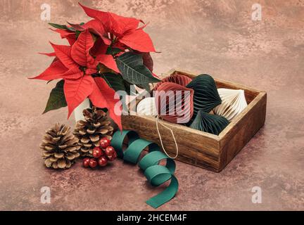 Rote Weihnachtsstern und Papierkugeln in Holzkiste Stockfoto