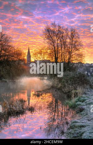 Die ersten Sonnenstrahlen eines frühen Morgens erleuchten den Himmel über der Stadt Malmesbury am Wiltshire-Hang. Stockfoto