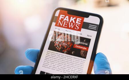 Online Corona Fake News auf einem Handy. Nahaufnahme, Mann beim Lesen gefälschter Nachrichten oder Artikel über covid-19 in einer Smartphone-Bildschirm-Anwendung. Stockfoto