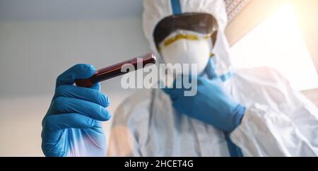 Medic in Schutzkleidung mit Blutprobe für Covid-19 Test für Antikörper im Labor Stockfoto