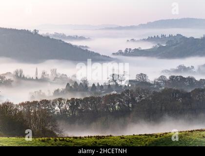 Großbritannien, England, Devonshire, Teign Valley. Morgennebel, der über dem Turm der Doddiscombsleigh Church im Tal unten liegt. Stockfoto