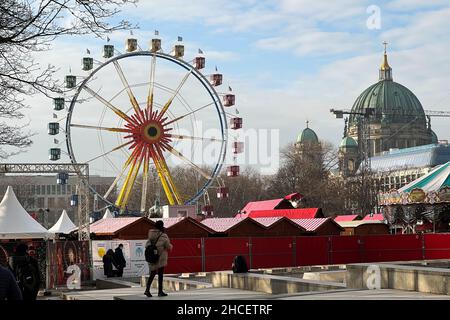 An einem sonnigen Wintertag dreht sich das Riesenrad auf einem Weihnachtsmarkt am Alexanderplatz in Berlin. Stockfoto