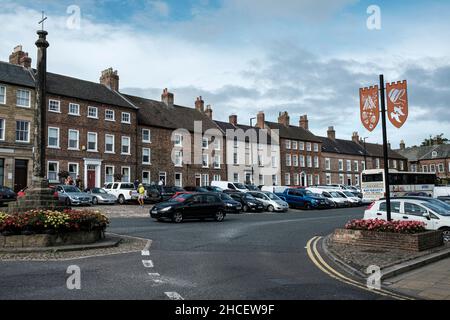 Bedale High Street mit Marktkreuz und dekorativen Schilden, North Yorkshire, England Stockfoto