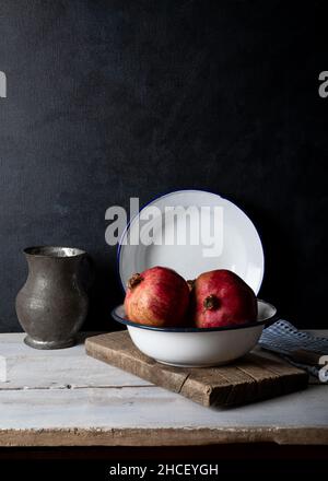 Frische Pomegrantes in weißer Schale auf Holzhintergrund. Stockfoto