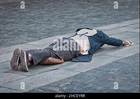 Tibetische Pilgerin, die auf dem Boden liegt, nachdem sie sich niedergewurmt hat. Die 'Barkhor Kora' machen, eine hingebungsvolle Pilgerreise um das Äußere des alten Jokhan Stockfoto
