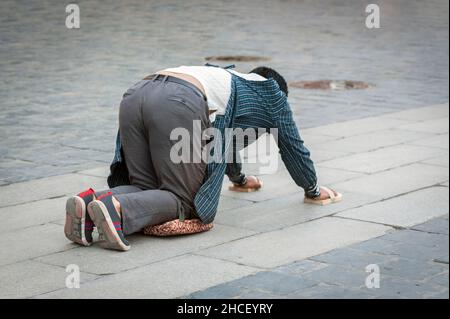 Tibetische Pilgerin, die auf dem Boden liegt, nachdem sie sich niedergewurmt hat. Die 'Barkhor Kora' machen, eine hingebungsvolle Pilgerreise um das Äußere des alten Jokhan Stockfoto