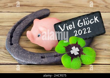 Glückssymbole Marzipan Piggy und Kleeblatt mit deutschem Glück 2022 auf Holzhintergrund Stockfoto