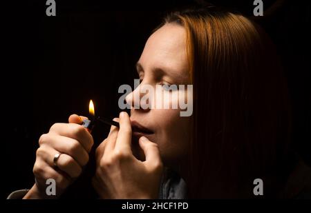 Frau raucht Marihuana, Cannabis durch ein Gerät auf schwarzem Hintergrund. Stockfoto