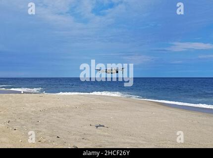 Kleine Drohne schwebt über Point angenehmer Strand, während Möwen starren, an einem teilweise sonnigen Herbsttag -01 Stockfoto