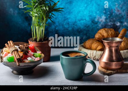 Schwarzer Kaffee, der in einem kupfertürken gebraut wird. Kaffeeeinstellung auf dem Tisch. Kaffee und Süßigkeiten. Vorderansicht. Stockfoto