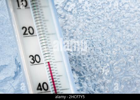 Das Thermometer zeigt eine niedrige Temperatur von minus 30 Celsius an. Wettervorhersage. Ein frostiger Tag und Eismuster auf dem Glas Stockfoto