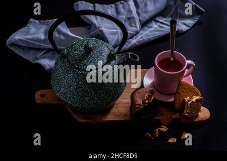 Valentinstag erfrischendes hausgemachtes Frühstück für ein älteres Paar mit grüner Teekannen aus Keramik, Schokoladenkeksen und herzförmigen Keks mit einem Vintage-Lo Stockfoto