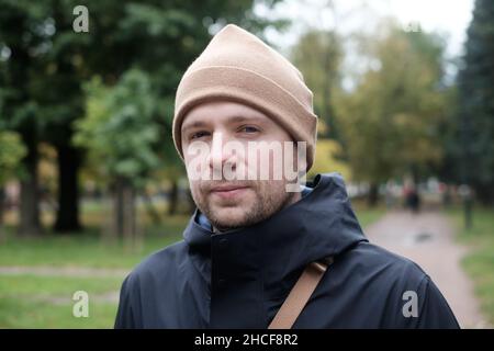 Junger Kaukasier, der die Kamera im Park ansieht Stockfoto