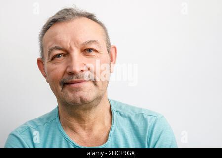 Porträt eines freundlichen älteren Mannes mit Schnurrbart. Ein grauhaariger Mann lächelt und schaut auf die Kamera Stockfoto