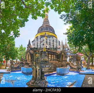 Der alte Singha-Löwe bewacht den Chedi des Wat Pa Pao-Tempels, versteckt in einem üppigen grünen Garten in Chiang Mai, Thailand Stockfoto