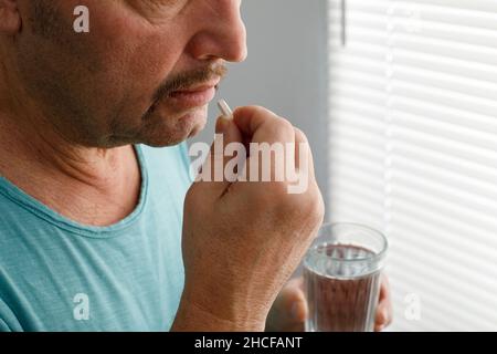 Ein Mann, der an einem Kater leidet, nimmt Medikamente gegen einen Kater. Stockfoto