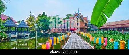 Der Garten des Wat Jedlin-Tempels blickt auf den malerischen See, bedeckt mit Lotuspflanzen, einer alten Bambusbrücke mit bunten Stofflaternen, einem kleinen Sommer Stockfoto