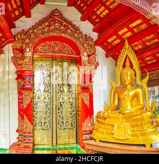 Das farbenfrohe Panorama der Fassade des Wat Phan Waen Viharn mit dem vergoldeten Buddha-Bild, geschnitztem Türrahmen und der mit Gol dekorierten Meistertür Stockfoto