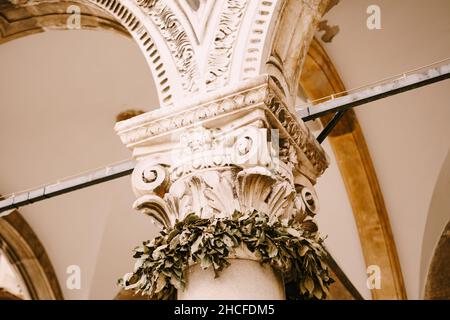 Fragment einer geschnitzten weißen Marmorsäule unter der gewölbten Decke. Nahaufnahme Stockfoto