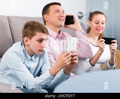 Eltern und Sohn, die Telefone benutzen Stockfoto