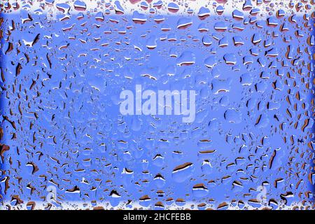 Nahaufnahme von Wassertropfen auf blauem Hintergrund in gemustertem Rahmen, Textur mit Tropfen auf Glasoberfläche. Leer für Design Stockfoto