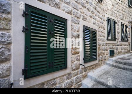 Kunststofffensterläden in einem Wohngebäude mit Steinwänden Stockfoto