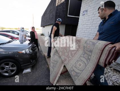 Austin, TX, USA. 2nd Oktober 2021. Zwei afghanische Männer tragen einen gestifteten Teppich in ihre Wohnung im Norden von Austin. Drei Monate lang werden Flüchtlinge, die vor den Unruhen in Afghanistan fliehen, nach Texas umgesiedelt, wobei viele alleinstehende Männer, große Familien mit Kindern, unter Dutzenden von Wohnungen in Austin, Texas, settelten. Religiöse Gruppen haben sich verstärkt, um die Bemühungen um die Einrichtung von Häusern für Hunderte von Flüchtlingen zu koordinieren. (Bild: © Bob Daemmrich/ZUMA Press Wire) Stockfoto