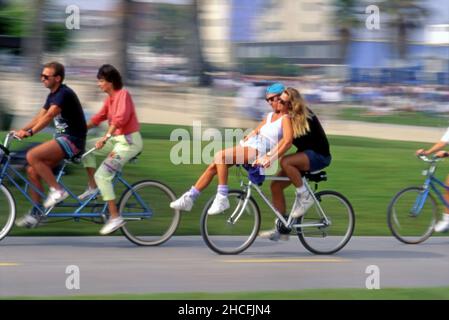 Paare, die sich Fahrräder auf dem Radweg in Venice Beach, Kalifornien teilen Stockfoto