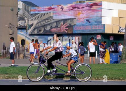 Mutter und Sohn reiten auf dem Radweg in der Nähe der Promenade am Venice Beach in Los Angeles, CA, ein Tandem-Fahrrad. Stockfoto