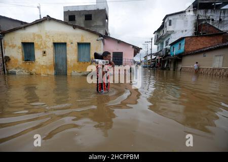 Bahia State, Brasilien. 28th Dez 2021. Am 28. Dezember 2021 durchläuft ein Mann eine mit Wasser bemundete Straße während einer Überschwemmung, die durch heftige Regenfälle in der Stadt Dario Meira, Bundesstaat Bahia, Brasilien, verursacht wurde. Laut einem Bericht der Zivilschutzbehörden des Bundesstaates Bahia stieg die Zahl der Todesopfer durch schwere Regenfälle, die den nordöstlichen brasilianischen Bundesstaat Bahia heimgesucht haben, am Montag auf 20 an, wobei 358 Menschen verletzt wurden. Nach Angaben des Nationalen Instituts für Meteorologie wird sich die hohe Regenmenge, die das südliche Bahia seit November verwüstet hat, diese Woche fortsetzen und bis in den Januar hinein ausdehnen. Quelle: Xinhua/Alamy Live News Stockfoto