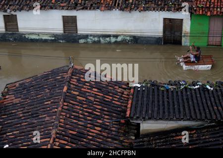 Bahia State, Brasilien. 28th Dez 2021. Am 28. Dezember 2021 paddelt ein Mann auf einem provisorischen Floß durch eine mit Wasser bemundete Straße während einer Überschwemmung, die durch heftige Regenfälle in der Stadt Dario Meira, Bundesstaat Bahia, Brasilien, verursacht wurde. Laut einem Bericht der Zivilschutzbehörden des Bundesstaates Bahia stieg die Zahl der Todesopfer durch schwere Regenfälle, die den nordöstlichen brasilianischen Bundesstaat Bahia heimgesucht haben, am Montag auf 20 an, wobei 358 Menschen verletzt wurden. Quelle: Xinhua/Alamy Live News Stockfoto