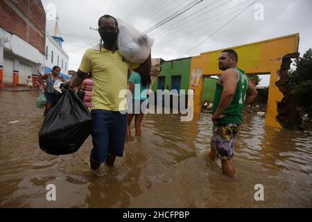 Bahia State, Brasilien. 28th Dez 2021. Am 28. Dezember 2021 laufen Menschen auf einer wasserverlaufenden Straße, während Überschwemmungen durch starke Regenfälle in der Stadt Dario Meira, Bundesstaat Bahia, Brasilien, verursacht wurden. Laut einem Bericht der Zivilschutzbehörden des Bundesstaates Bahia stieg die Zahl der Todesopfer durch schwere Regenfälle, die den nordöstlichen brasilianischen Bundesstaat Bahia heimgesucht haben, am Montag auf 20 an, wobei 358 Menschen verletzt wurden. Nach Angaben des Nationalen Instituts für Meteorologie wird sich die hohe Regenmenge, die das südliche Bahia seit November verwüstet hat, diese Woche fortsetzen und bis in den Januar hinein ausdehnen. Quelle: Xinhua/Alamy Live News Stockfoto