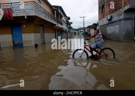 Bahia State, Brasilien. 28th Dez 2021. Ein Junge fährt am 28. Dezember 2021 auf einer wasserverlaufenden Straße mit dem Fahrrad während der Überschwemmungen, die durch heftige Regenfälle in der Stadt Dario Meira im brasilianischen Bundesstaat Bahia verursacht wurden. Laut einem Bericht der Zivilschutzbehörden des Bundesstaates Bahia stieg die Zahl der Todesopfer durch schwere Regenfälle, die den nordöstlichen brasilianischen Bundesstaat Bahia heimgesucht haben, am Montag auf 20 an, wobei 358 Menschen verletzt wurden. Nach Angaben des Nationalen Instituts für Meteorologie wird sich die hohe Regenmenge, die das südliche Bahia seit November verwüstet hat, diese Woche fortsetzen und bis in den Januar hinein ausdehnen. Quelle: Xinhua/Alamy Live News Stockfoto