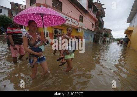 Bahia State, Brasilien. 28th Dez 2021. Am 28. Dezember 2021 laufen Menschen auf einer wasserverlaufenden Straße, während Überschwemmungen durch starke Regenfälle in der Stadt Dario Meira, Bundesstaat Bahia, Brasilien, verursacht wurden. Laut einem Bericht der Zivilschutzbehörden des Bundesstaates Bahia stieg die Zahl der Todesopfer durch schwere Regenfälle, die den nordöstlichen brasilianischen Bundesstaat Bahia heimgesucht haben, am Montag auf 20 an, wobei 358 Menschen verletzt wurden. Nach Angaben des Nationalen Instituts für Meteorologie wird sich die hohe Regenmenge, die das südliche Bahia seit November verwüstet hat, diese Woche fortsetzen und bis in den Januar hinein ausdehnen. Quelle: Xinhua/Alamy Live News Stockfoto