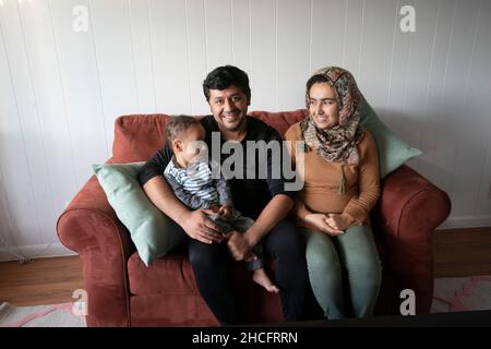 Austin Texas USA, November 2021: Ein afghanisches Paar und ihr junger Sohn posieren in ihrer neuen Wohnung in der Nähe der University of Texas in Austin. Flüchtlinge, die vor den Unruhen in Afghanistan fliehen, werden weiterhin in Texas umgesiedelt, wobei viele alleinerziehende Männer und große Familien mit Kindern in Wohnungen in ganz Austin ziehen. Religiöse und andere gemeinnützige Gruppen haben sich verstärkt, um die Bemühungen zur Einrichtung von Häusern für Hunderte von Flüchtlingen zu koordinieren. ©Bob Daemmrich Stockfoto