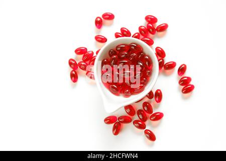 Krillöl rote Gelatine Kapseln in weißer Keramik Tasse auf weißem Hintergrund.Omega-Fettsäuren.gesunde Ernährung und Nahrungsergänzungsmittel Stockfoto