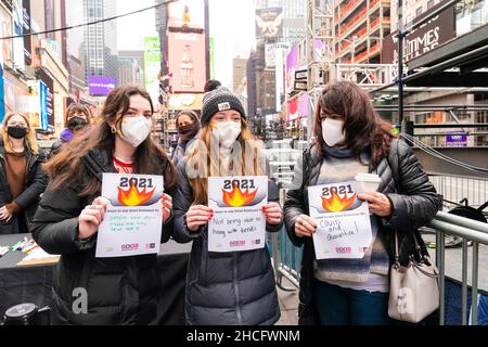 New York, NY - 28. Dezember 2021: Touristen aus Rhode Island halten mitten auf dem Times Square während des Good Riddance Day Papiere mit einer Nachricht in der nach lateinamerikanischer Tradition eingestellten Verbrennungsanlage Stockfoto