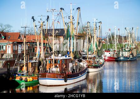 Greetsiel, Deutschland. 15th Dez 2021. An einer Kaimauer im historischen Hafen der Stadt liegen zahlreiche Krabbenschneider. Der Mangel an Fängen und die niedrigen Erzeugerpreise haben die Krabbenfischer an der deutschen Nordseeküste im zweiten Corona-Jahr 2021 weiterhin vor Probleme gestellt. (To dpa: Leere Netze und niedrige Erzeugerpreise verursachen Probleme für Krabbenfischer) Quelle: Hauke-Christian Dittrich/dpa/Alamy Live News Stockfoto