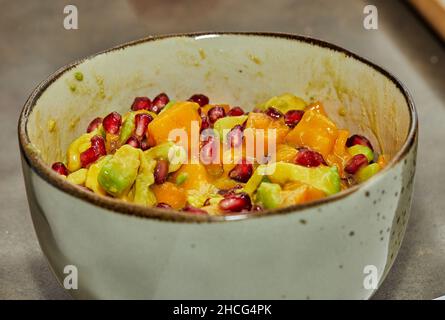 Fertigfruchtsalat mit Avocado, Mango und Granatapfel in einer Schüssel in der Küche. Stockfoto