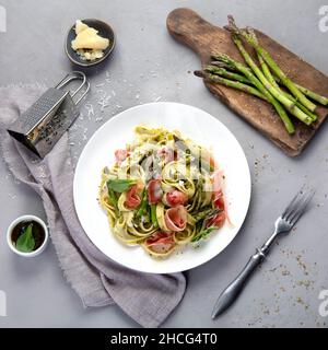 Pasta mit Spargel und Prosciutto auf grauem Hintergrund. Traditionelles italienisches Food-Konzept. Draufsicht, flach liegend Stockfoto