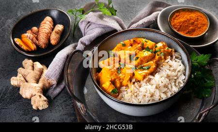 Indisches Butterhuhnfleisch mit Basmati-Reis auf dunklem Hintergrund. Traditionelles hausgemachtes Food-Konzept. Stockfoto