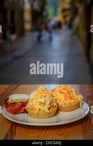 Traditionelle Pintxos mit russischem Salat und Serrano-Iberico-Schinken-Tostada auf einem Tisch im Freien an einer Bar in der Altstadt von San Sebastian, Baskenland, Spanien Stockfoto