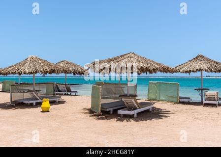 Hurghada, Ägypten - 02. Juni 2021: Sonnenschirme und Liegestühle an einem leeren Strand in Makadi Bay, einer von Ägypten schönen Roten Meer Riviera. Stockfoto