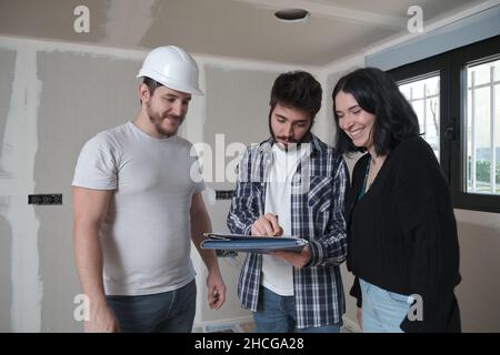 Ehemann eines jungen Paares, das ein Dokument für den Kauf eines Hauses im Bau unterzeichnet hat. Stockfoto