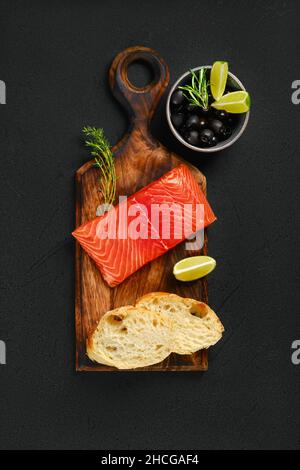 Draufsicht auf ein Stück frisches Lachssteak mit Ciabatta und würziger Kräutersauce Stockfoto