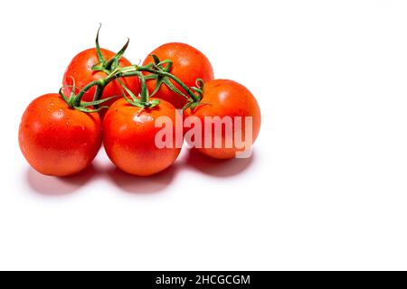 Foto eines Straußes von fünf nassen roten natürlichen Tomaten auf weißem Hintergrund.das Foto ist im horizontalen Format aufgenommen und hat Platz für Kopien. Stockfoto