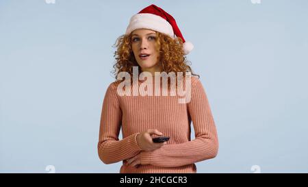 Überraschte Frau in santa hat Film isoliert auf blau zu sehen Stockfoto