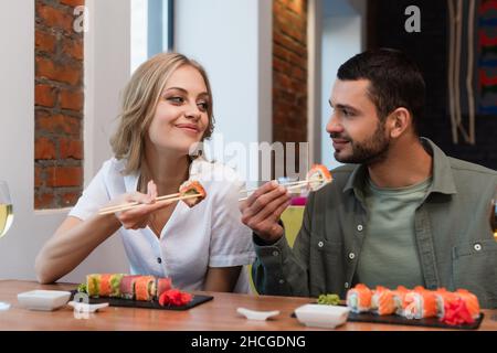 Ein zufriedenes Paar, das sich ansah, während es im Restaurant leckeres Sushi aß Stockfoto