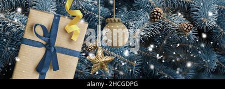 Neujahrs- und Weihnachtsgrusskarte oder Webbanner, Hintergrund. Geschenkbox auf blauem weihnachtsbaum mit Zapfen und rustikalen Retro-Dekorationen. Stockfoto